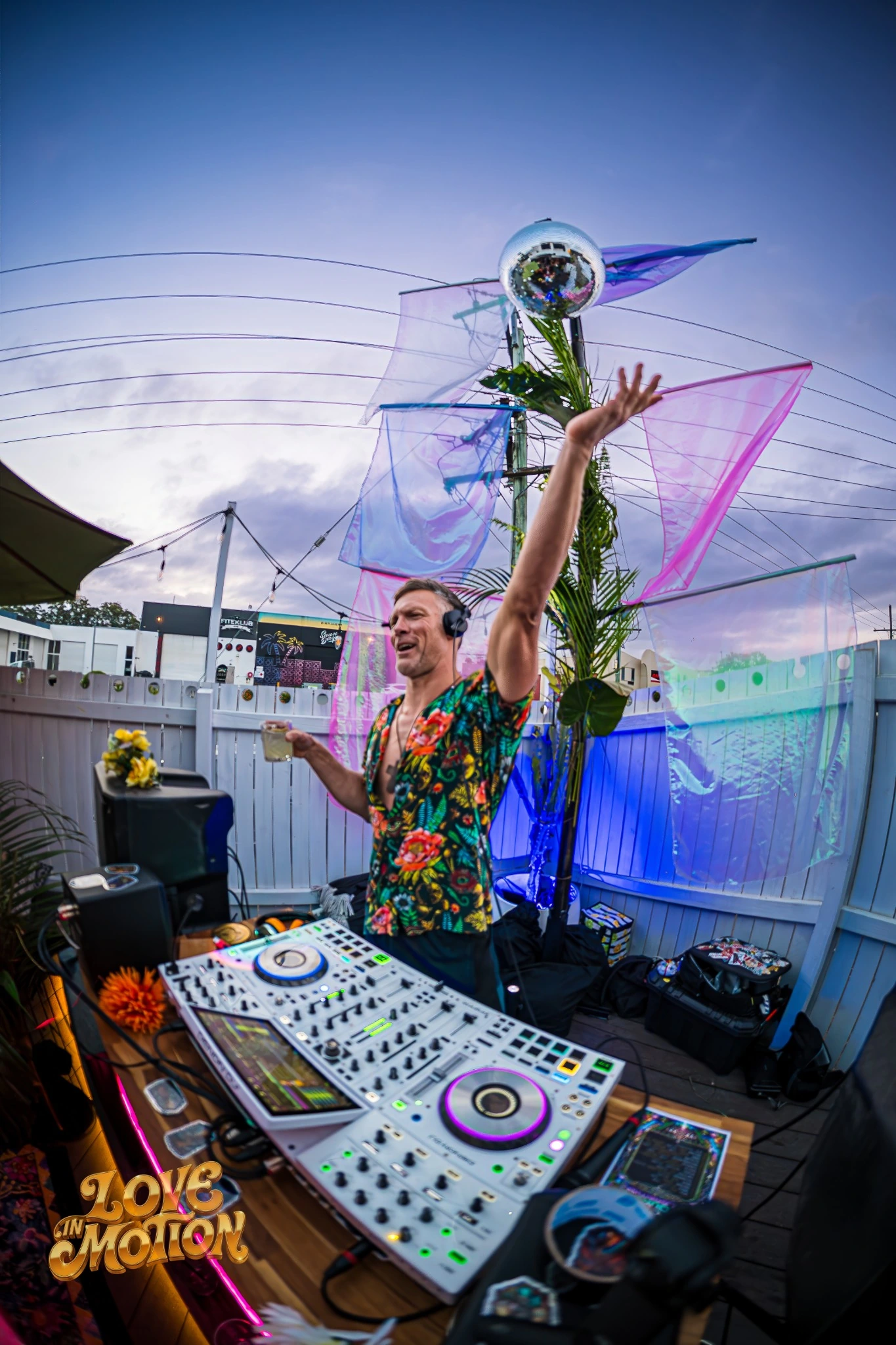 Tim raising a mirror ball above the DJ decks at Love in Motion